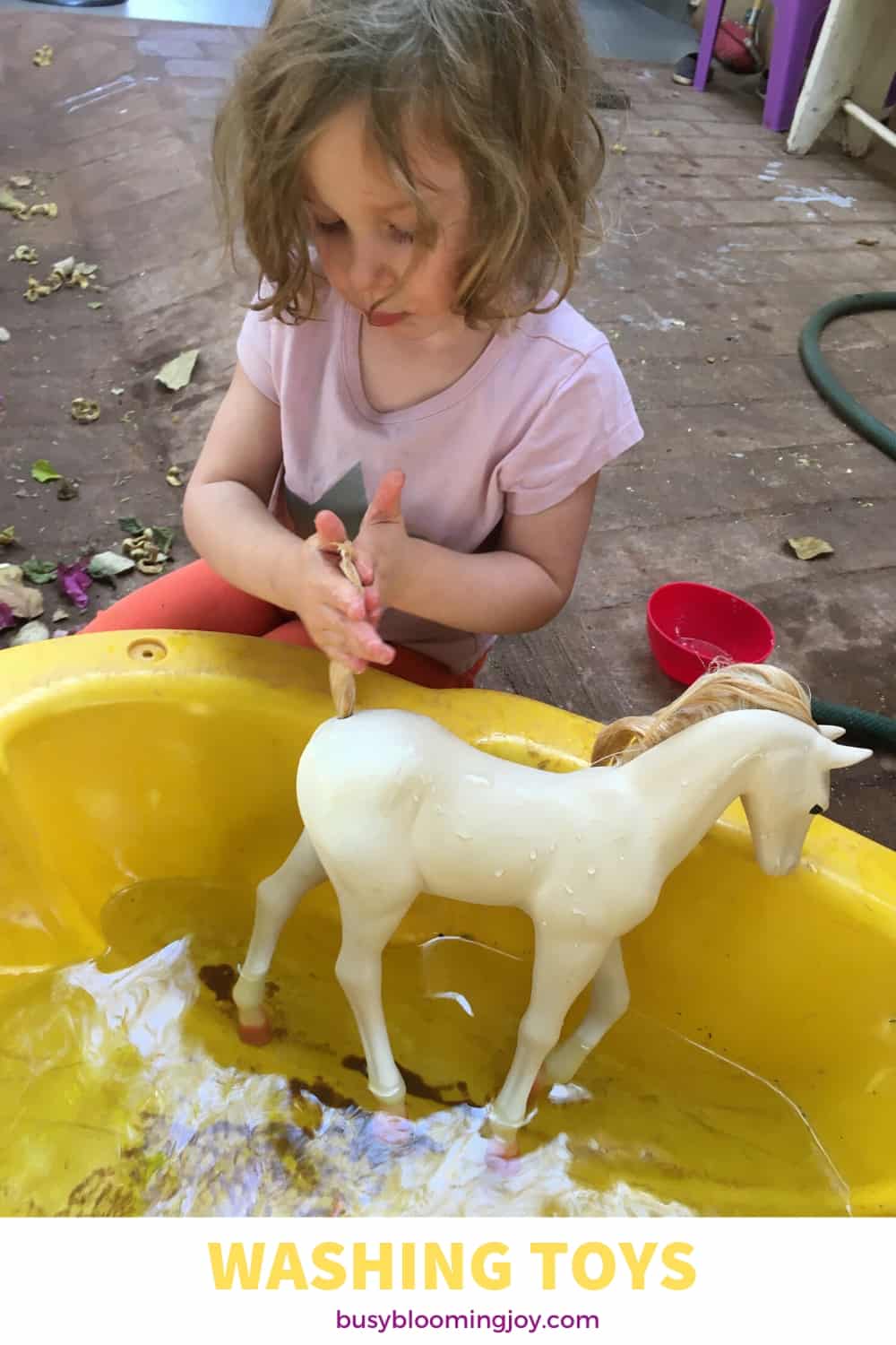 Preschooler washing her toys as an outdoor activity