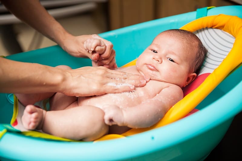 A tub bathing a newborn in a bathtub with newborn insert