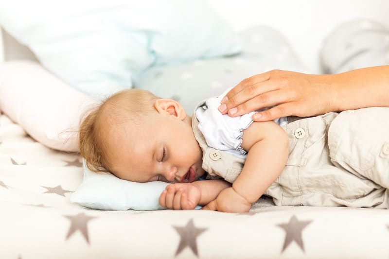 Side-lying and patting (plus a swaddle and minus the pillow) can help settle baby fully to sleep in the bassinet, avoiding the need to transfer