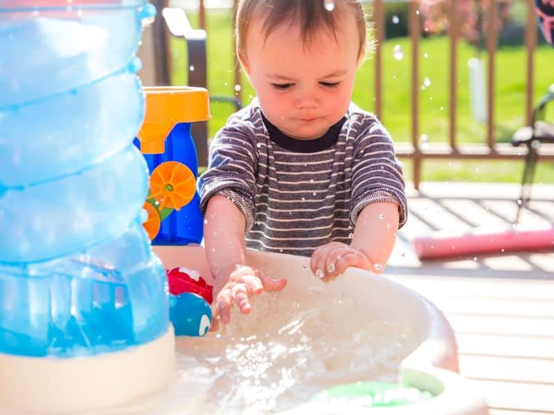 playing with water can stimulate all senses for a toddler