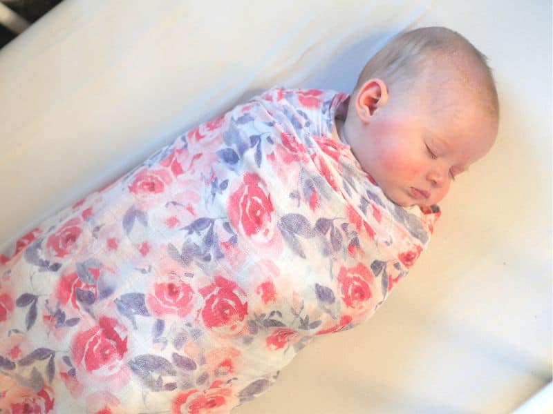 Newborn wrapped up snugly in her swaddle