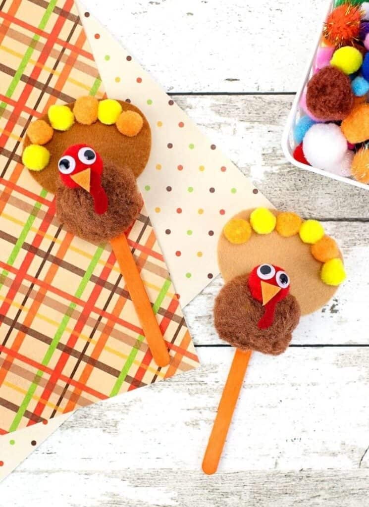 Pom pom turkey craft made with felt, pom poms, and popsicle sticks